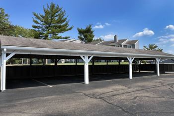 A covered parking lot with a building in the background